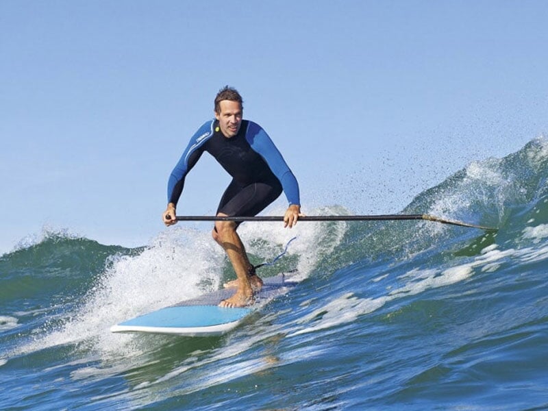 un homme surfe une vague en paddle