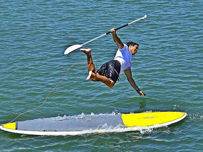 un homme saute de sa planche de paddle