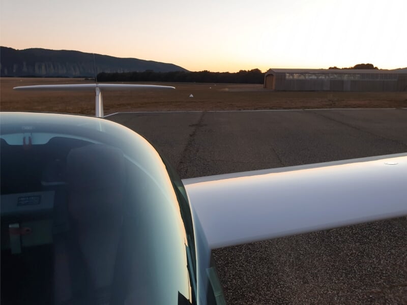 Cockpit et aile d'un planeur stationné sur la piste de l'aérodrome de Château-Arnoux au coucher du soleil.