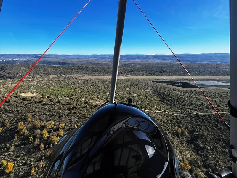 Cockpit d'un ULM avec vue sur un paysage désertique et des montagnes à l'horizon sous un ciel bleu clair.