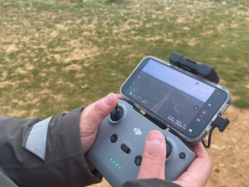 Télécommande de drone en gros plan, tenant un smartphone affichant la vue de la caméra du drone en vol