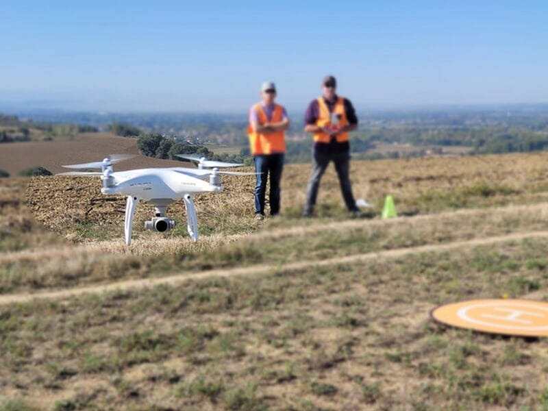 Drone en vol avec deux personnes en arrière plan