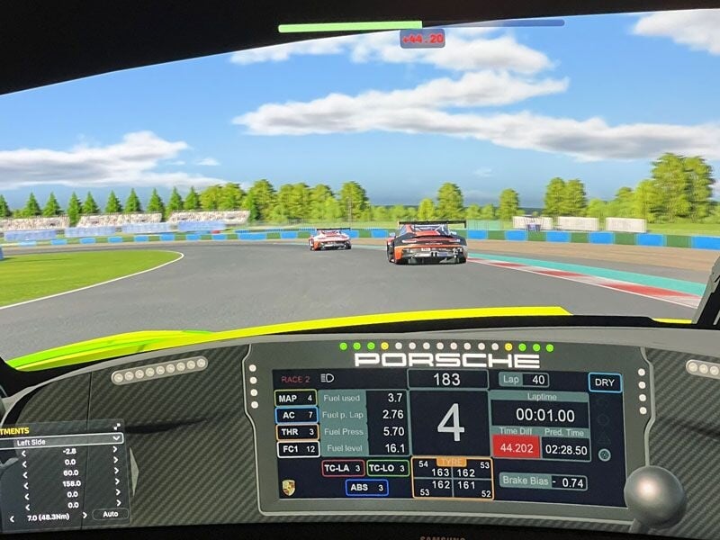 Vue depuis le cockpit d'un simulateur de conduite automobile avec affichage numérique et piste de course virtuelle.