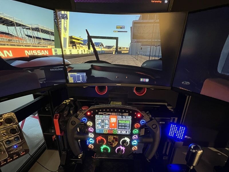 Cockpit d'un simulateur de course automobile avec volant high-tech et plusieurs écrans de contrôle.