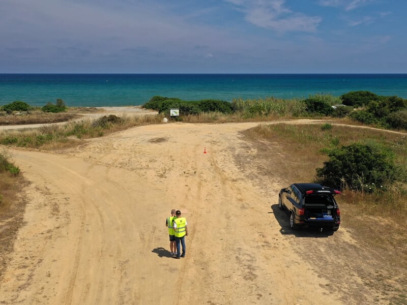 deux télépilotes de drone se tiennent debout sur un terrain dégagé près d'une voiture