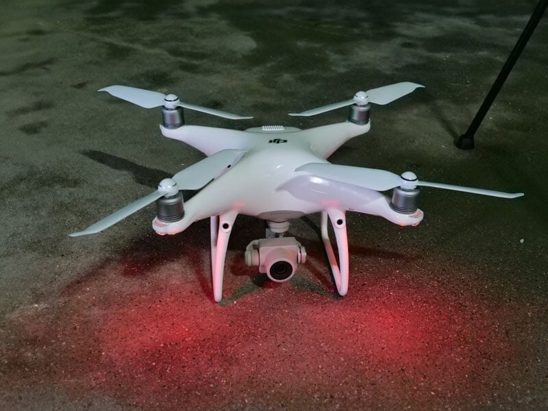 Drone de loisir blanc posé sur un sol de gravier