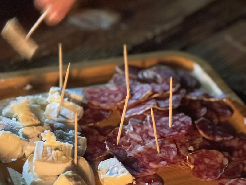 Plateau en bois avec assortiment de charcuterie et fromages, chacun piqué avec un cure-dent