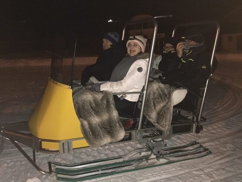 Quatre personnes assises sur un traîneau à neige avec des couvertures en fourrure la nuit.