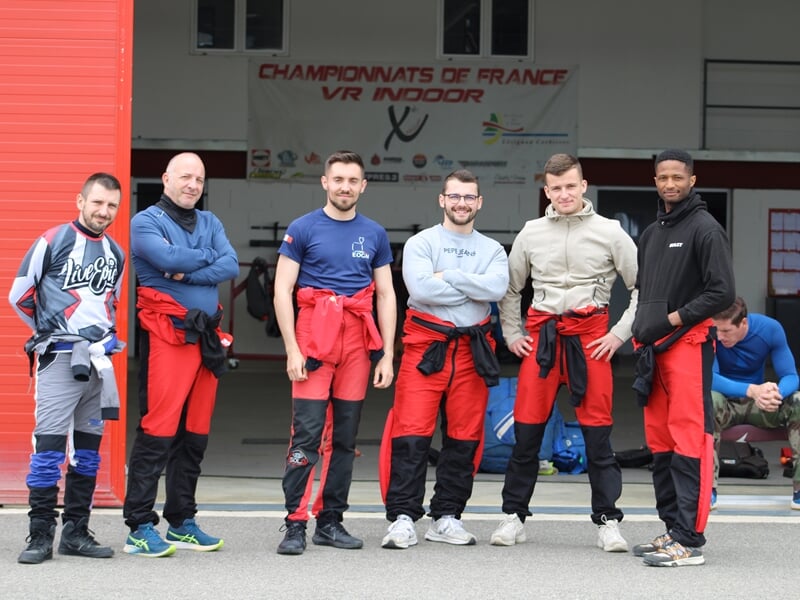 Équipe de parachutistes posant devant un hangar avec une banderole des