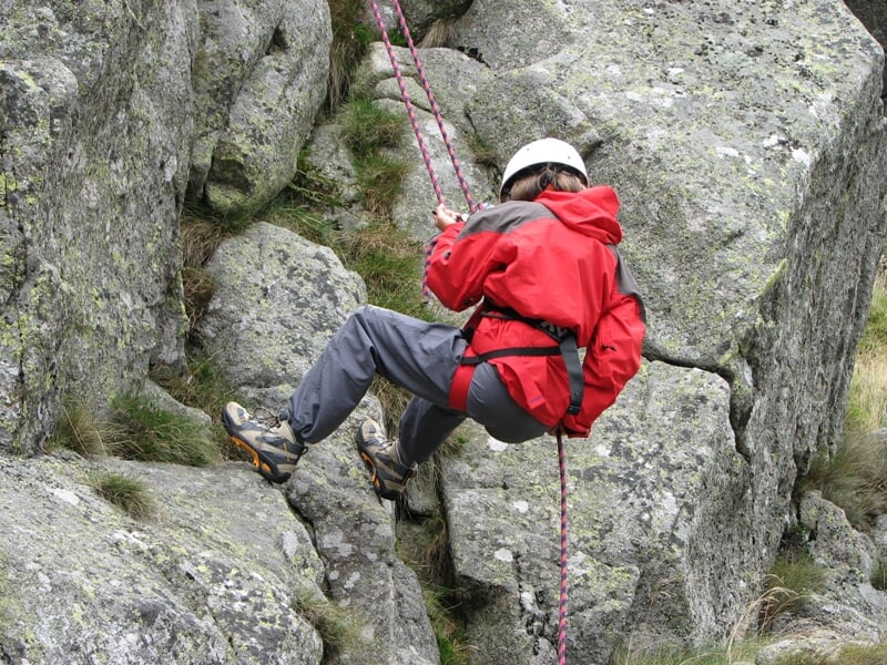 personne pratiquant la descente en rappel