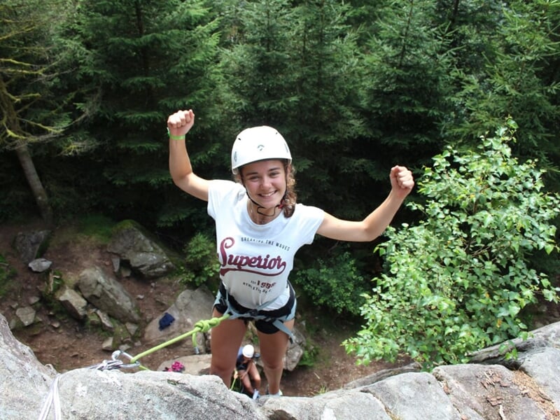 Personnes fière d'être arrivée en haut du falaise avec équipement d'escalade et arbres en contrebas