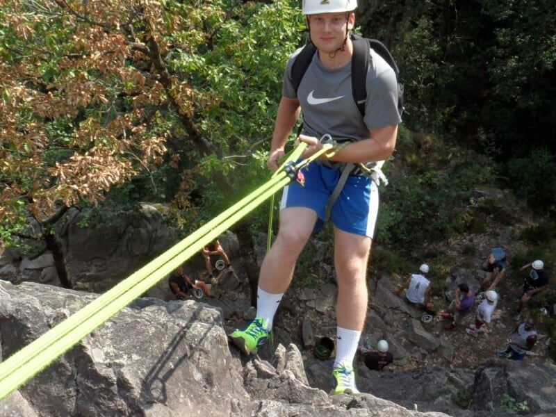 Personnes en descente en rappel sur une falaise rocheuse avec groupe de personnes en contrebas