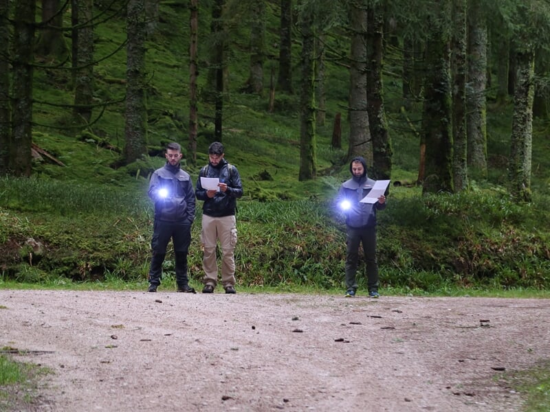 Trois personnes apprenant la pratique du morse avec une lampe torche