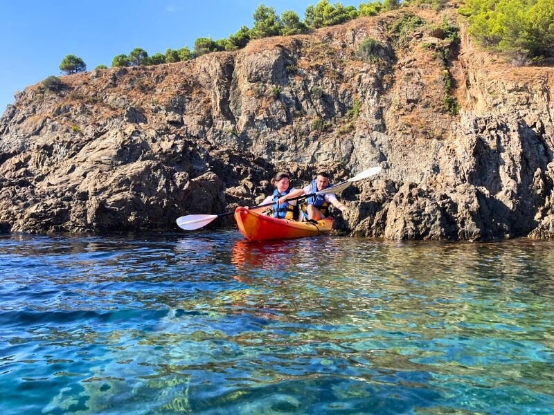 Un kayak de mer double avec deux kayakistes en bord de mer.