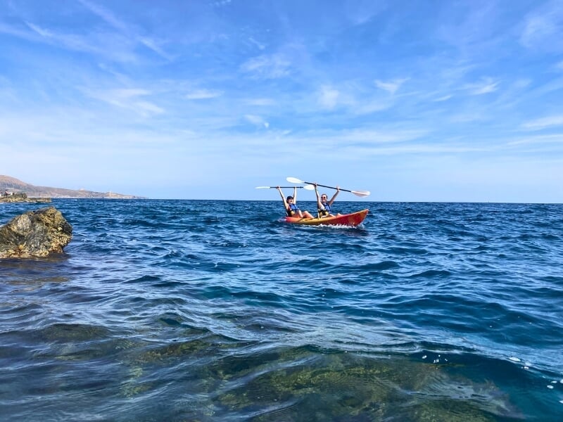 Deux kayakistes sur un kayake double lèvent leurs pagaies en signe de victoire.