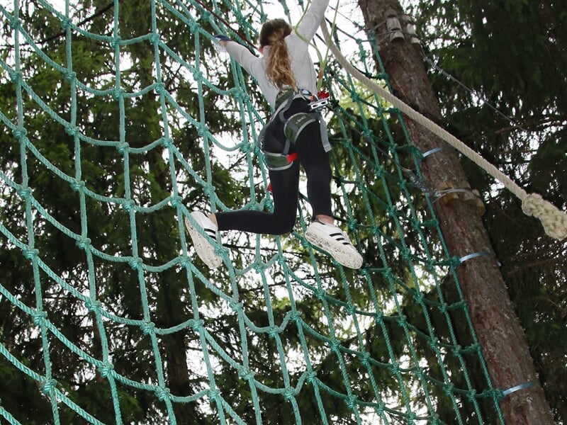 enfant grimpant à un filet dans un accrobranche