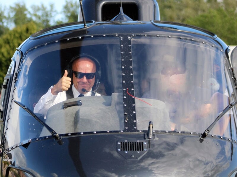 un pilote d'hélicoptère fait un signe de la main depuis le poste de pilotage de l'appareil