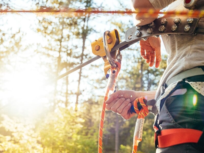 focus sur le système de sécurité d'un accrobranche au soleil couchant