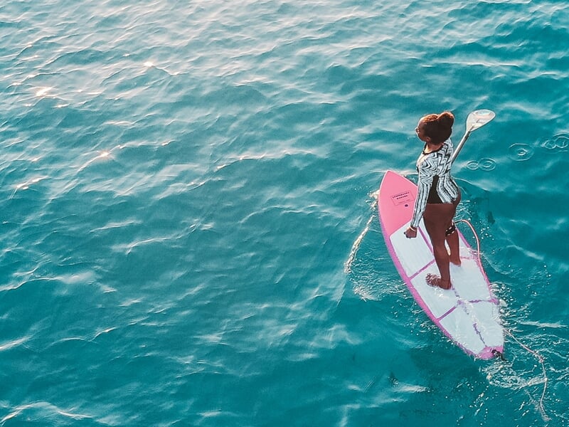 Femme sur Stand Up Paddle glissant sur l'eau avec sa pagaie