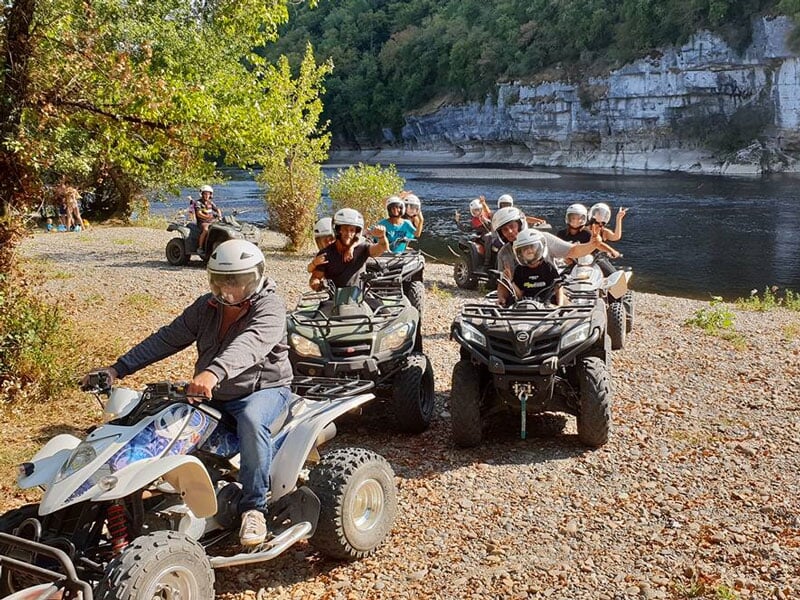 un groupe de pilotes de quads posent au bord d'une rivière