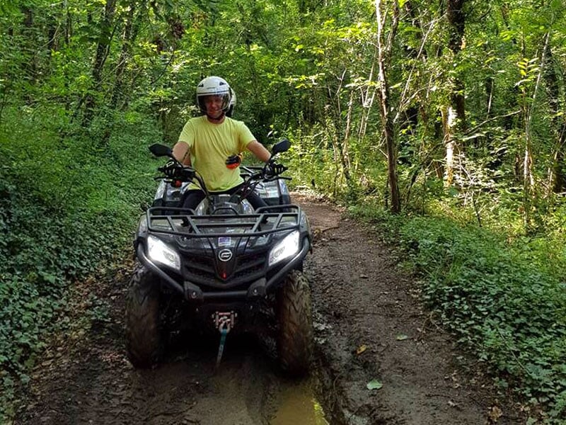 un pilote de quad roule sur un sentier en pleine forêt