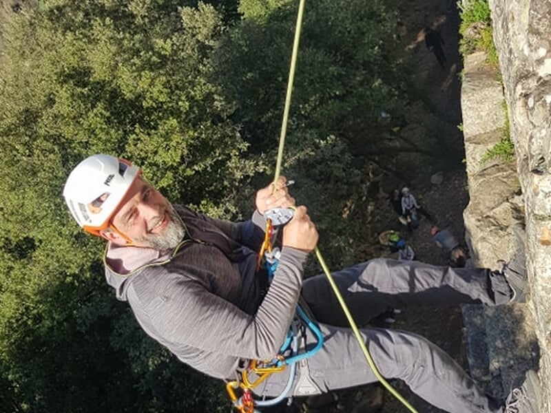 homme effectuant une descente en rappel à même une paroi rocheuse