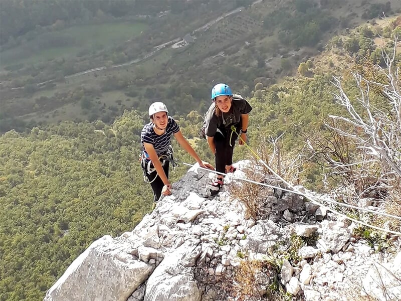 deux personnes prennent la pause devant un paysage naturel au sommet d'une paroi de pierre