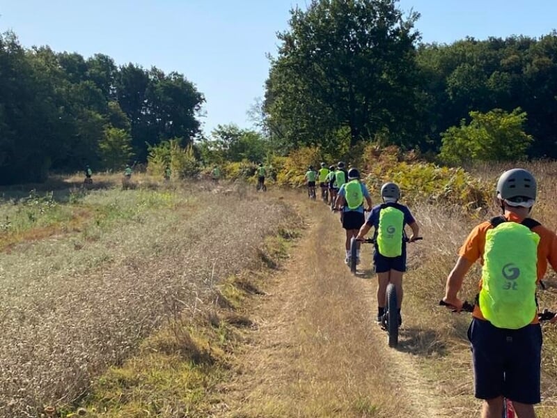 Un groupe de personnes conduisant des trottinettes électriques sur un chemin de campagne à travers champs.