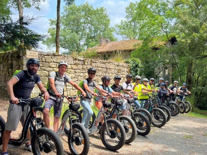 Un groupe de personnes alignées sur le départ d'une randonnée en trottinette électrique.