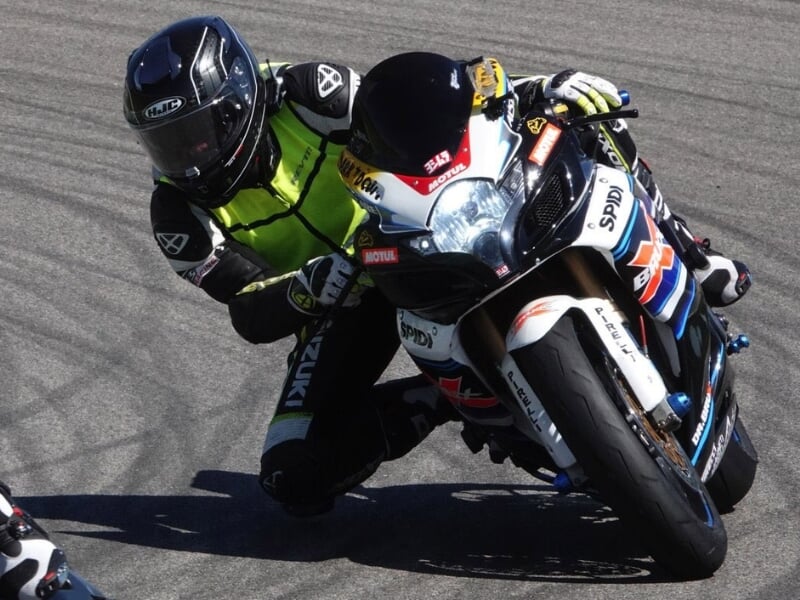 Pilote de moto penché dans un virage serré d'un circuit.
