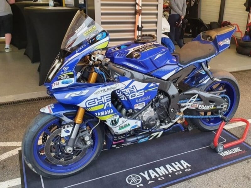 Une moto de course Yamaha bleue exposée sur un circuit.