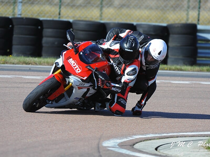 Moto sportive en pleine courbe avec deux pilotes portant des combinaisons assorties.