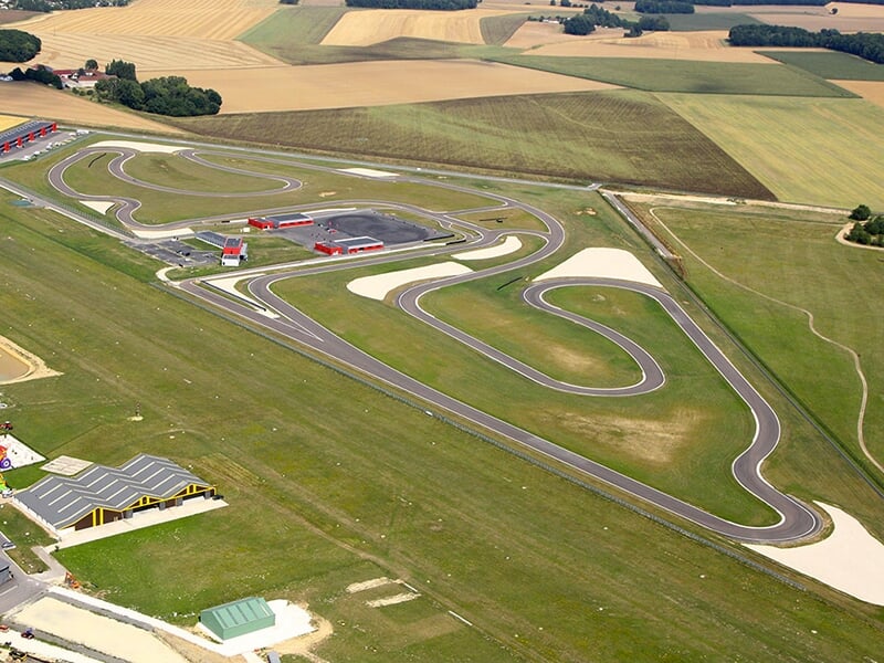 Vue aérienne d'un circuit de course avec des bâtiments et des pistes sinueuses.