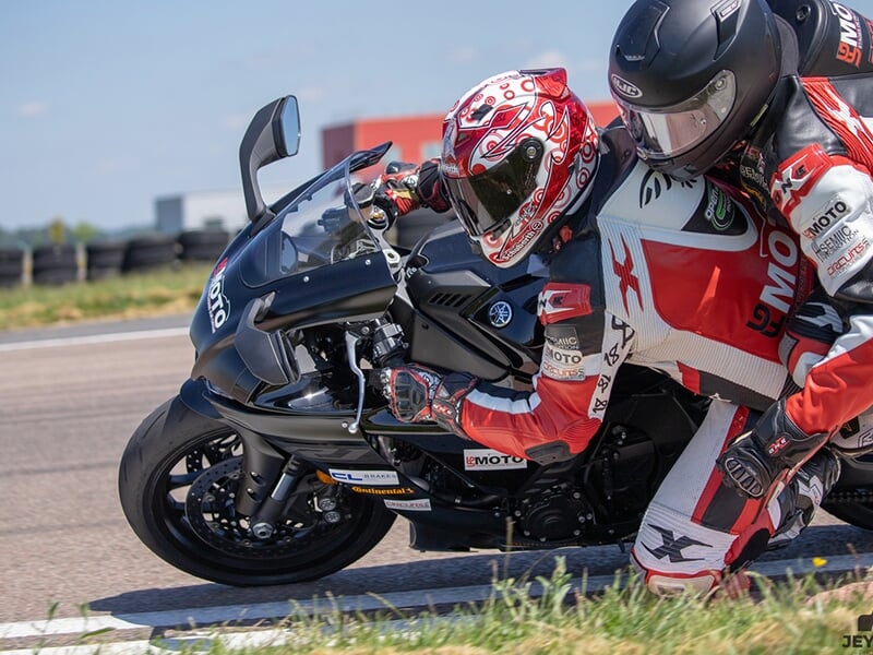 Gros plan sur une moto noire en pleine action, pilotes concentrés sur la piste.