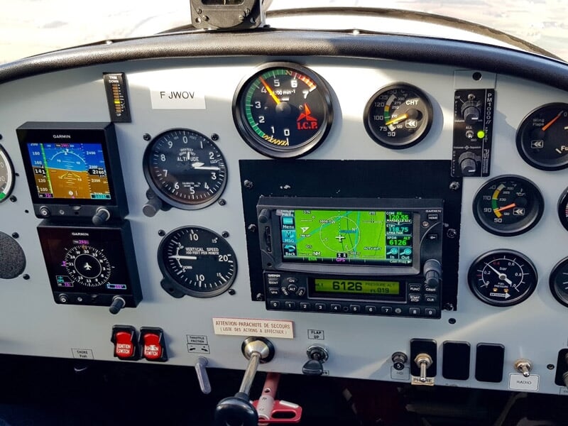 Tableau de bord d'un avion ULM avec plusieurs instruments de vol et un écran de navigation affichant une carte.