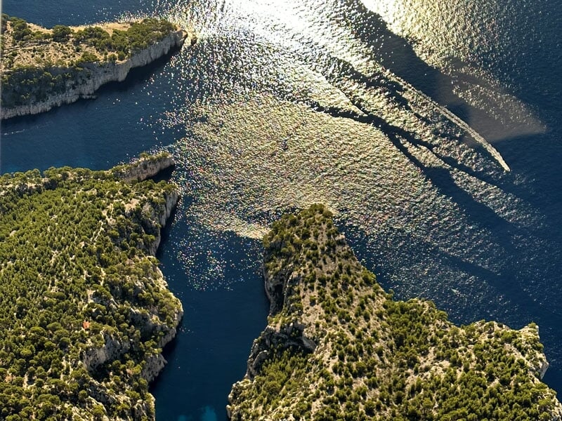Reflets scintillants du soleil sur la mer Méditerranée à la Calanque de Port-Pin, avec des formations rocheuses verdoyantes et des criques profondes