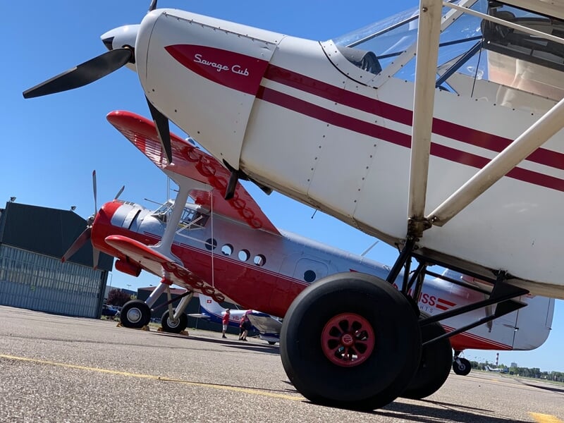 Gros plan sur le train d'atterrissage d'un avion léger blanc et rouge stationné sur une piste d'aéroport.