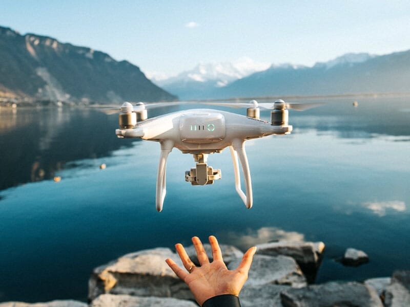 Drone volant au-dessus d'un lac calme avec montagnes en arrière-plan, main tendue vers le bas