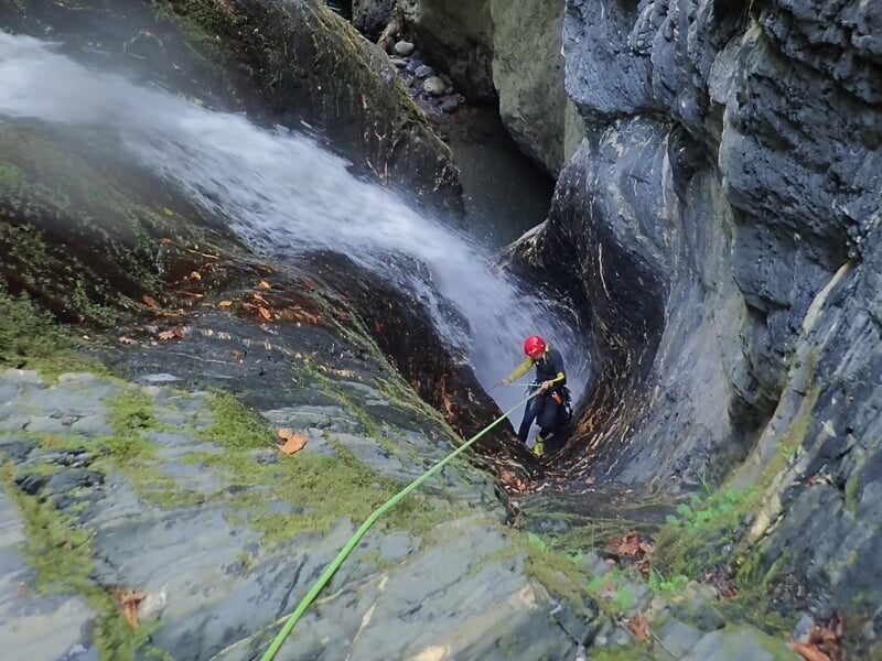 homme descendant en rappel dans un canyon avec cascade