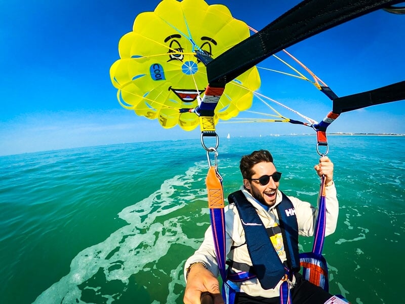 Un homme faisant du parachute ascensionnel en solo avec un parachute jaune vif arborant un visage souriant