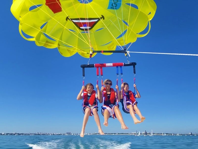 Une femme et deux enfants faisant du parachute ascensionnel ensemble au-dessus de l'océan