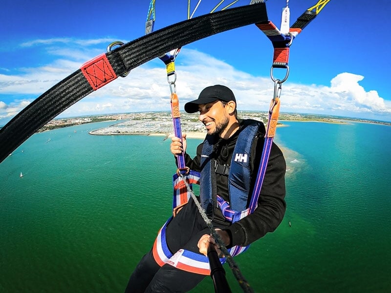 Un homme faisant du parachute ascensionnel en solo au-dessus d'une zone côtière avec une vue sur le littoral et l'eau en dessous