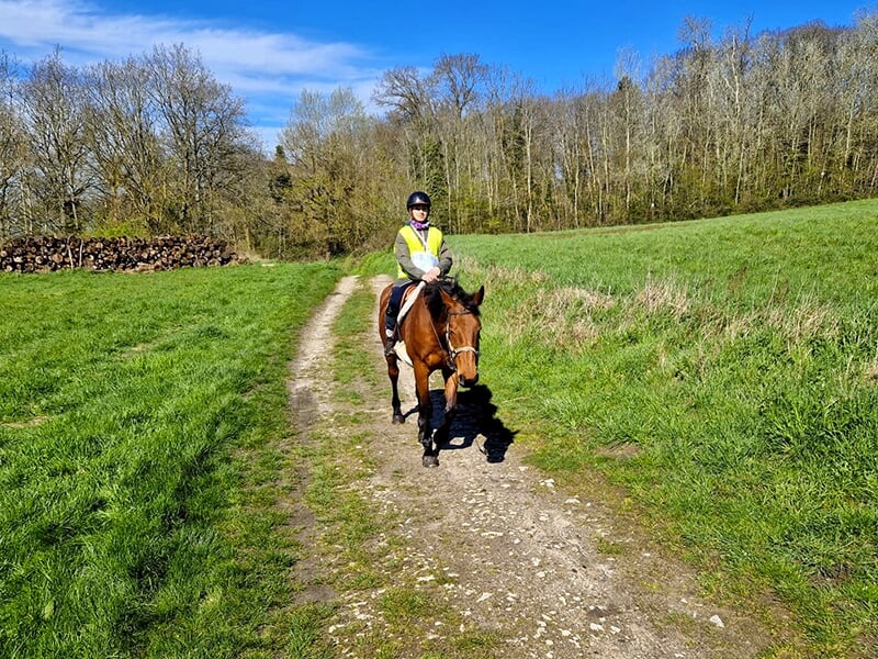 Cavalière portant un casque d'équitation sur un chemin de randonnée équestre