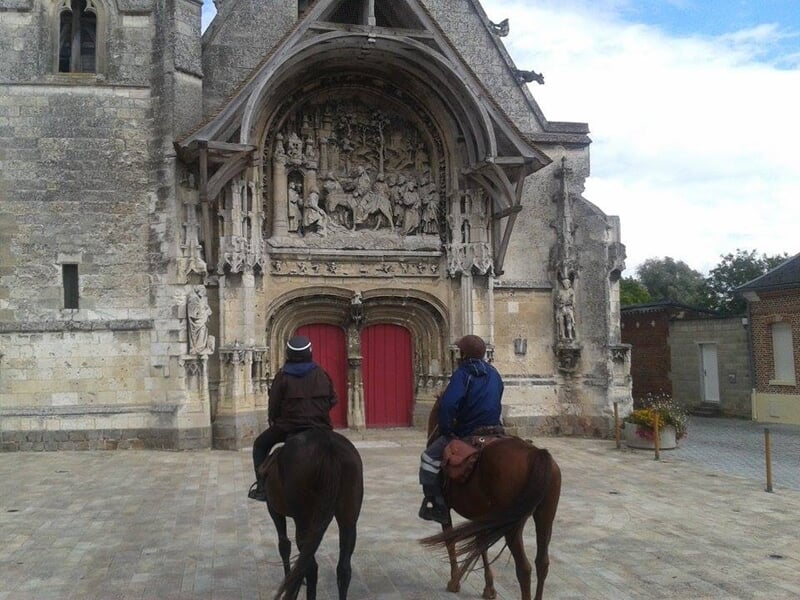 Deux personnes à cheval devant l'église de la Neuville