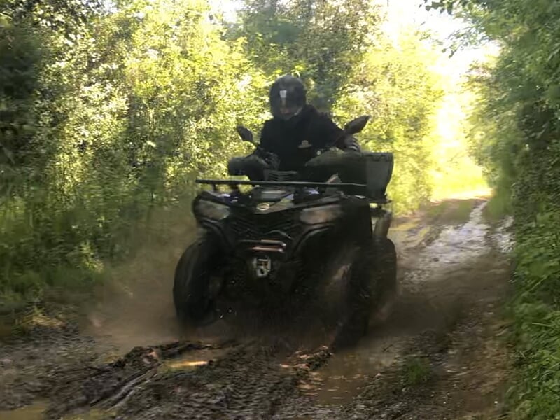 Un fan de sports mécaniques s'essaient au quad sur le sol détrempé d'un chemin forestier