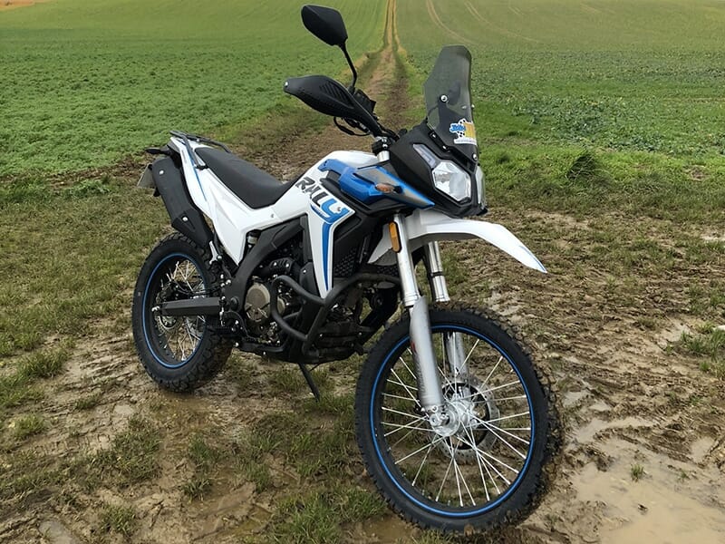 Une moto tout terrain Voge 300 Rally à l'arrêt sur un sentier boueux au milieu de la campagne