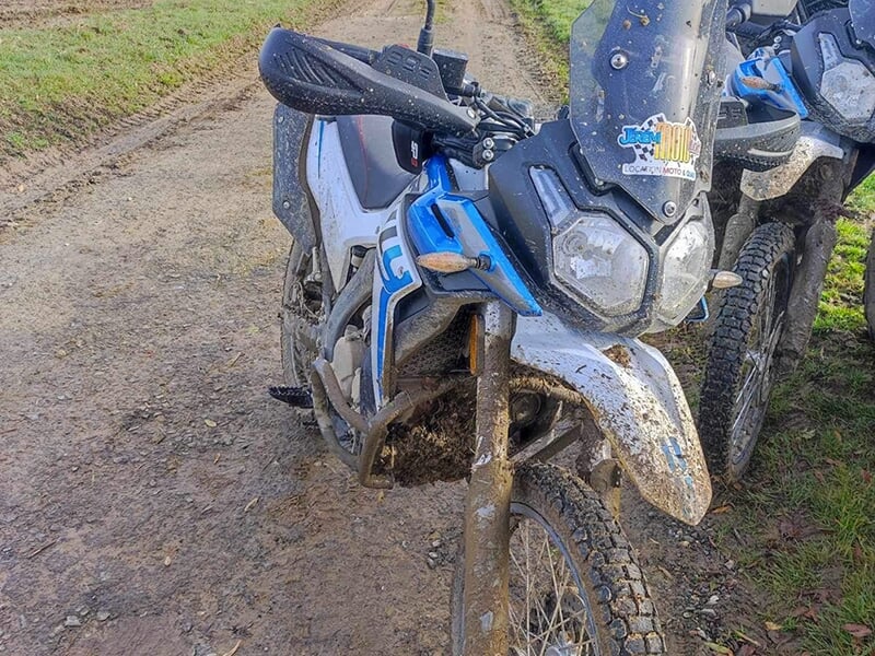 Deux motos tout-terrain couverte de boue à l'arrêt sur un chemin de terre.
