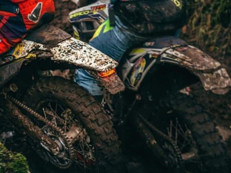 Vue arrière de deux motos-cross couvertes de boue après une session d'enduro