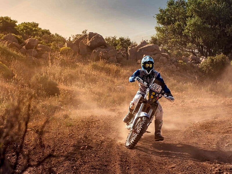 Moto d'enduro faisant une pointe de vitesse sur une piste de terre en pleine nature