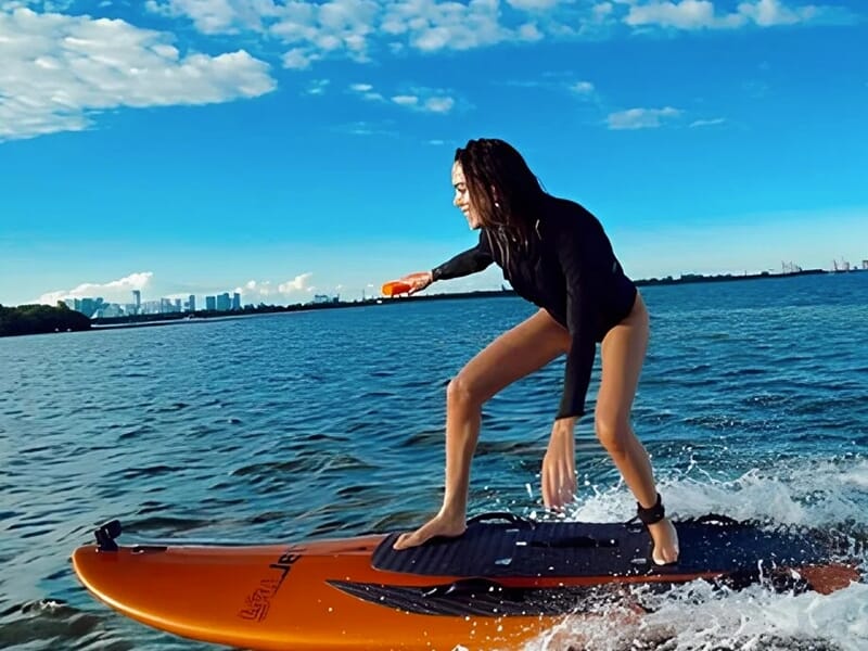 Surfeuse pratiquant le surf électrique motorisé avec une télécommande à la main